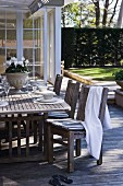 Festively set table on wooden terrace and towel draped over chair on summer day