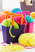 Balls of brightly coloured wool in purple plastic bags with wool-wrapped handles