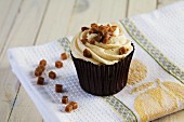 A caramel cupcake decorated with toffee pieces