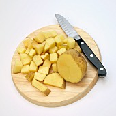 Diced Yukon gold potato on a chopping board with a knife