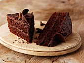 Two slices of chocolate cake on a wooden plate
