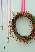 Willow and rose hip wreath hanging from pink ribbon