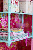 Storage boxes and linen on wall-mounted shelves painted pale turquoise