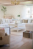 Sofa set and rustic, white-painted wooden coffee table in corner of country-style living room