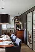 Dining room with dark walls and deer antler decor, view of the kitchen