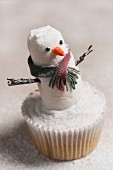 A snowman cupcake with icing sugar for Christmas