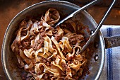 Tagliatelle Bolognese (Bandnudeln mit Hackfleisch-Tomaten-Sauce) in Topf mit Nudelzange