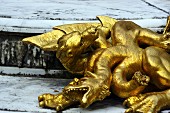 Vergoldete Drachenfiguren auf Steinboden im Versailler Schlosspark