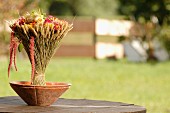 Bouquet of flowers and ears of wheat in clay bowl on garden table