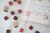 Wrapped gifts with old-fashioned, hand-crafted address labels and black alphabet and number stamps on white, vintage wooden surface