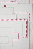 Stamped borders of dots in pink and pale grey on white envelopes