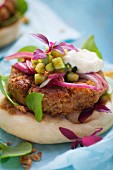 Chickpea burgers on unleavened bread with red onions, cucumber and a yoghurt suace
