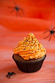 A chocolate cupcake topped with orange buttercream for Halloween
