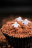 A chocolate cupcake decorated with ghosts for Halloween