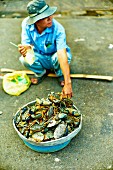 A man selling crustaceans at a market in Saigon (Vietnam)