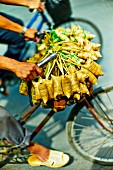 A vendor cycling with bunches of banana leaf parcels to a market in Saigon (Vietnam)