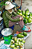 Frau verkauft Früchte auf einem Markt in Saigon (Vietnam)