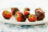Strawberries dipped in dark chocolate on a white plate