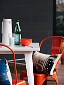 Cushions with artistic prints on orange vintage chairs around table on terrace