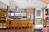 Offene Küche mit Holzfronten an Schränken und Theke, Barhocker, im Wohnraum mit traditionellem Flair
