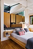 Modernes Bett mit Kissenstapel vor Nische mit Tagesliege in zeitgenössischem Wohnhaus