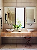 Modern floating washstand with two countertop basins below mirrors flanking window