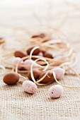 Pink and brown mini chocolate eggs with straw on a piece of jute