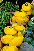 Bright yellow pattypan squashes between broccoli and mange tout
