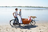 Paar mit Hund und Fahrrad auf dem Weg zum Strandpicknick