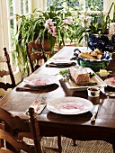 Set table in front of potted plants in bay window