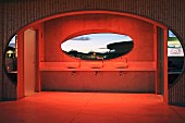 View through oval window aperture in minimalist washroom with dramatic lighting