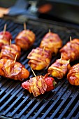 Stuffed mini peppers wrapped in bacon on a barbecue