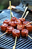 Sausage snails on skewers on a barbecue