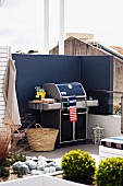Barbecue against screen wall painted dark blue on modern roof terrace