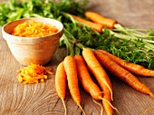 Whole organic carrots and a bowl of grated carrot