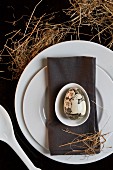 And Easter Place setting with a grey napkin and an artistically painted egg
