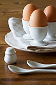 Drei braune Eier in Eierbechern aus weißem Porzellan