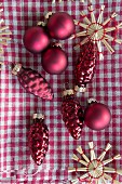 Red Christmas tree decorations and straw stars on gingham cloth