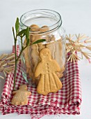 A jar of gingerbread on a cloth with mistletoe and straw stars