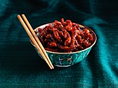 Crispy beef strips with chilli in an oriental bowls with chopsticks