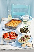 Various Greek appetisers: dolmadakia, tomatoes stuffed with rice, spanakopita, aubergine dip with olives
