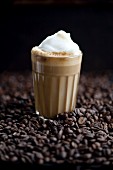 A glass of latte macchiato on coffee beans