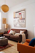Erdtöne im Wohnzimmer, Retro Sofa vor Wand mit Bild und gemütlicher Polstersessel auf rustikalem Dielenboden