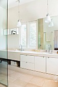 Bright bathroom with towel compartment and cupboard doors in masonry washstand below small pendant lamps