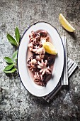 Boiled baby octopus with lemon wedges