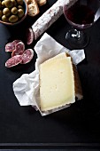 An arrangement of cheese, salami, olives and red wine