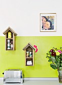 Vogelhäuschen als Gewürzregal an grün lackierter Wand in der Küche