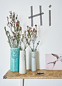 Danish designer vases on DIY chipboard shelf below greeting written in washi tape on wall