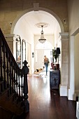 View from stairwell through archway of woman and dog in narrow hallway in grand villa