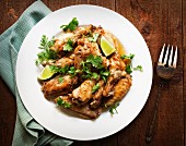 Jerk chicken wings with lime wedges and coriander